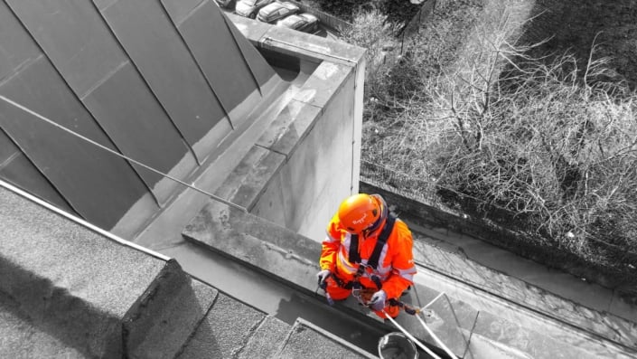 Rappel rope access technician undertaking gutter and drainage maintenance works