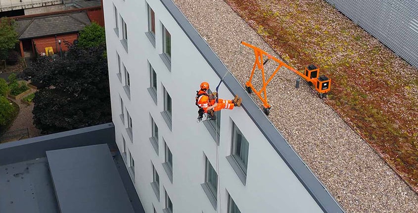 An IRATA Rope Access technician abseiling down a building