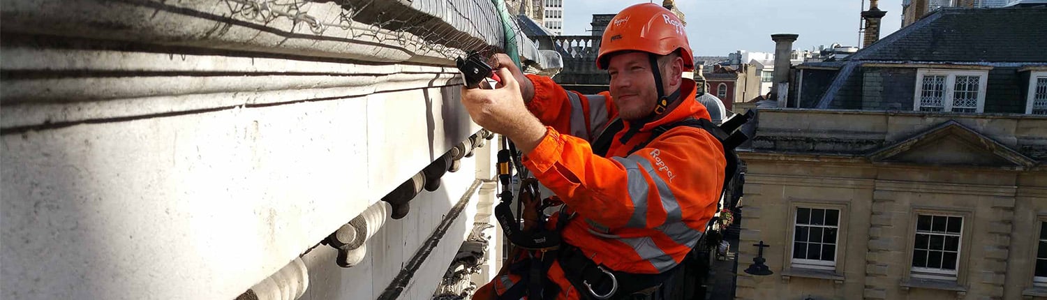 Rope Access technician installing bird netting on a building