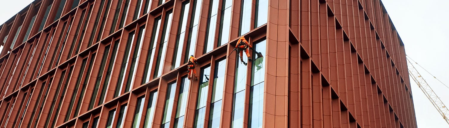 Two Rope Access technicians cleaning a building facade via abseiling