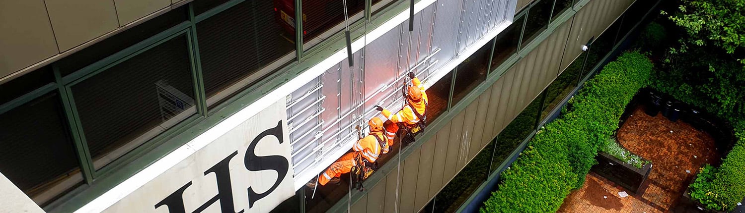 Two Rope Access technicians removing an advertising banner