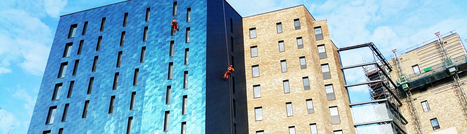 Two IRATA Rope Access technicians abseiling down a building facade
